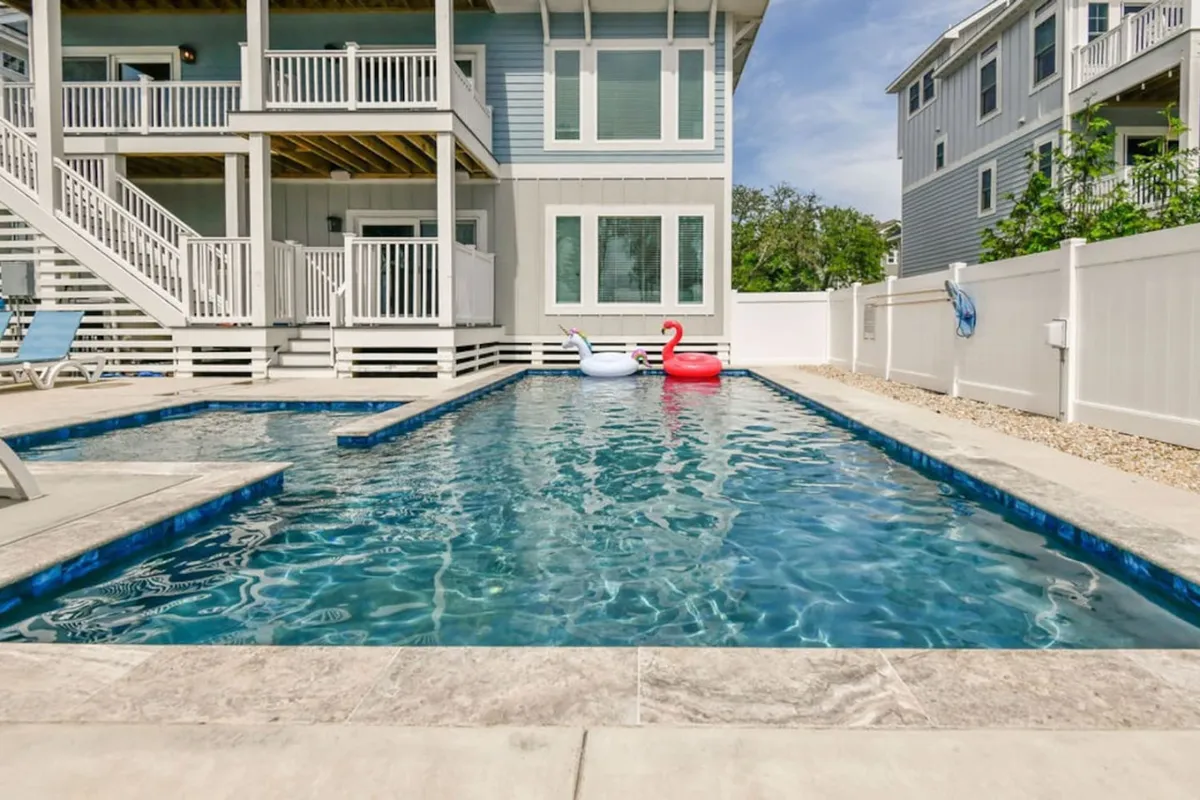 This image showcases a sparkling swimming pool surrounded by outdoor seating and playful pool floats, all set against the backdrop of the home's architecture. The inviting area suggests space for lounging, swimming, and socializing.