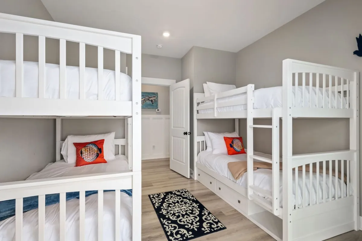 Bunk beds with cheerful decorative pillows and an area rug create a playful yet restful environment. The layout is clearly kid-friendly, offering a flexible sleeping arrangement ideal for families traveling with children.